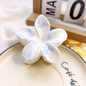 Detail view of a floral marble pattern hair claw clip on a decorative ceramic plate