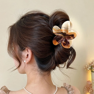 Elegant frangipani hair claw clip with brown marble pattern worn on a hair bun