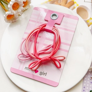 Détail d'élastiques à cheveux roses à nœud sur carte avec touches florales