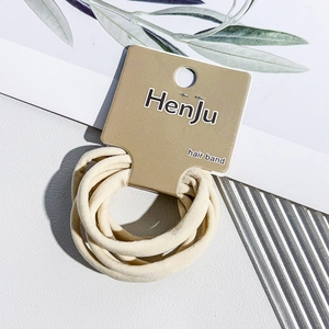 Close-up of cream-colored thick seamless elastic hair bands on a brown display card
