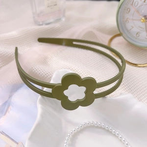 Vue détaillée d'un serre-tête floral vert foncé à texture mate sur un tissu blanc