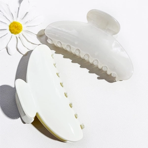 Detail of cream white and marble textured semicircular hair claws with glossy finish