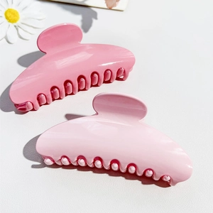 Close-up of pink semi-circle hair claws in glossy resin with floral decorative accent
