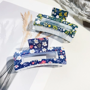 Detail showing two square shark clips with floral daisy patterns in blue and teal colors