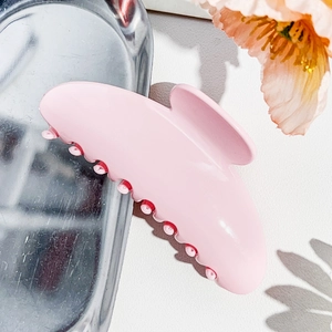 Close-up of pink matte hair claw clip on silver tray with decorative floral accent