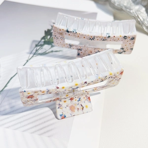 Detail view of two rectangle claw clips with floral UV prints and hollow design