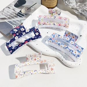 Detail view of four floral pattern rectangular hair claws on a decorative ceramic tray