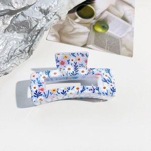 Detailed close-up of floral print hair claw clip with delicate daisy patterns