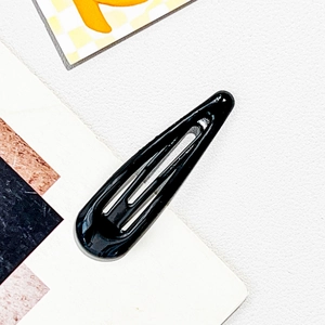 Close-up of classic black teardrop-shaped metal snap hair clip with smooth glossy finish
