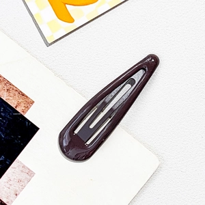 Detail of dark coffee drop-shaped hair clip with glossy finish and snap-on metal closure