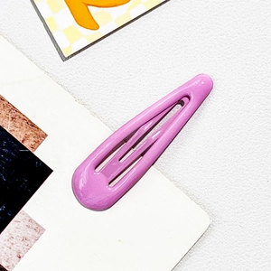 Macro shot of purple glossy metal snap clip with teardrop design on textured leather