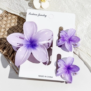 Detailed set of purple frangipani hair claws with glossy resin finish on white card