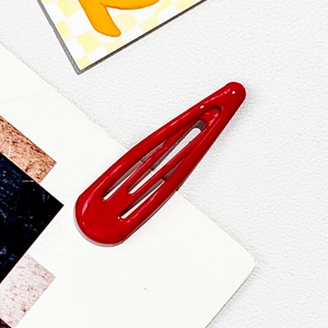 Detailed view of a glossy red metal drop hair clip with a polished lacquered finish