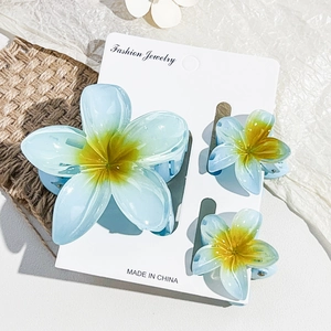 Detailed set of blue and yellow gradient frangipani flower hair clips on textured background