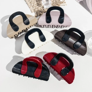 Flat lay of six contrast color hair claw clips in khaki, pink, cream, coffee, and black