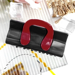Close-up of contrast color hair claw clip with black base and red U-shaped design