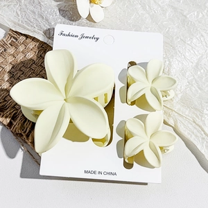 Detail of cream white matte flower hair claw clips set on rustic linen background