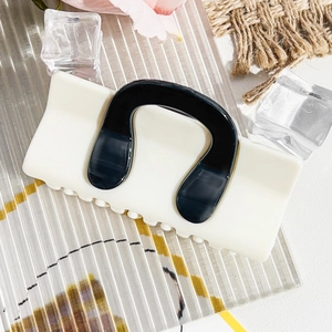 Detail view of cream white rectangular hair claw with black contrast U-shaped design