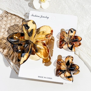 Detail view of amber resin floral hair claw clips on white display card with rustic decor