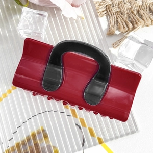 Macro shot of dark red and black square hair claw clip on textured background