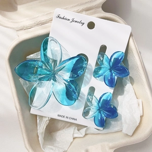 Detailed set of three gradient blue frangipani hair clips on a jewelry card