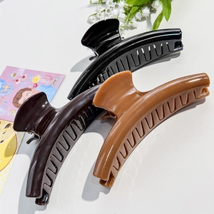 Close-up of three glossy large hair claws in black, chocolate brown, and caramel colors