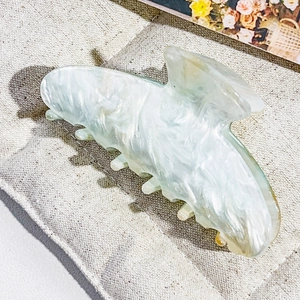 Detailed macro of a mint green marble butterfly hair claw clip on a linen texture