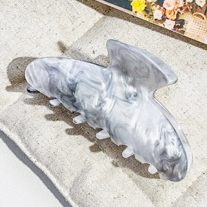 Detail of gray marbled butterfly hair claw clip on beige fabric background