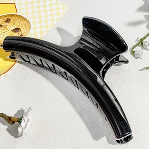 Close-up of a large black glossy hair claw clip with a sleek curved design and secure grip