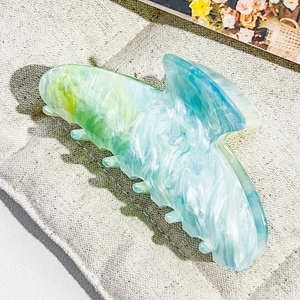 Detail view of a large marble texture hair claw clip in blue, green, and white colors