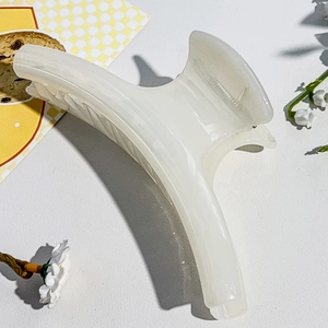 Close-up of a large cream white shark hair claw clip with a glossy pearlescent finish