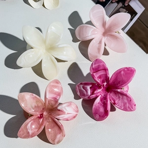 Dettaglio di quattro mollette a fiore in acetato con texture marmorizzata rosa e bianca