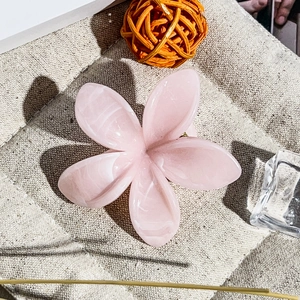 Vista dettagliata di una clip per capelli a fiore frangipani rosa con texture marmo