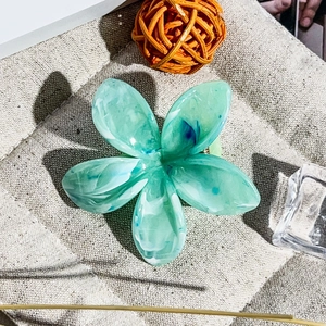 Dettaglio di fermaglio per capelli a fiore blu marmorizzato su fondo di iuta