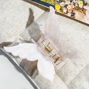 Detail of pink marble butterfly hair claw with a gold metal spring on fabric