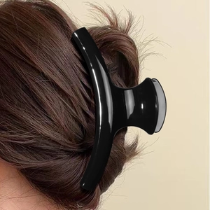 Glossy black hair claw clip for women featuring a minimalist curved design on brown hair