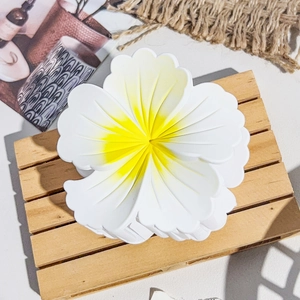 Détail de la pince à cheveux fleur de frangipanier blanche avec un dégradé jaune au centre