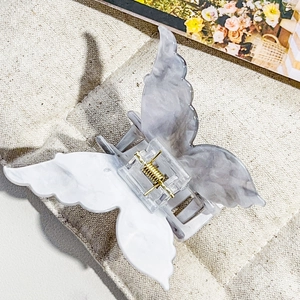 Detailed view of 3D butterfly hair claw with grey marble texture and gold spring