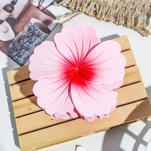 Détail d'une grande pince à cheveux fleur dégradé rose sur un petit plateau en bois
