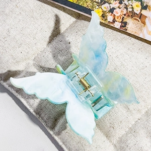 Detail of 3D butterfly hair claw clip with blue-green marble texture and gold metal spring