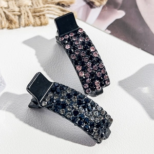 Detailansicht von zwei Strass-Haarspangen mit rosa und lila Kristallen auf schwarzer Basis