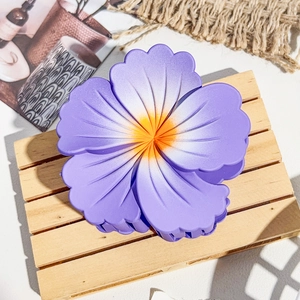 Détail d'une pince à cheveux en forme de fleur dégradé violet et jaune sur plateau bois