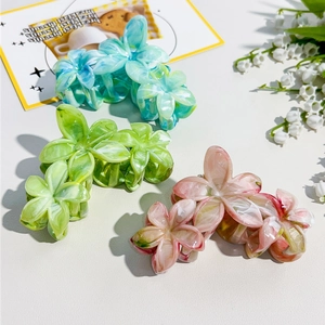 Detail of marble pattern flower hair claws in turquoise, soft green, and pink colors