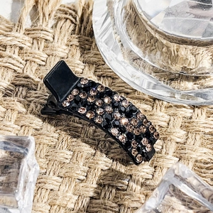 Detailaufnahme einer glitzernden Haarspange mit schwarzen und champagnerfarbenen Strasssteinen