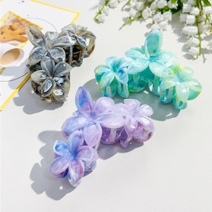 Detail of floral hair claws with marble textures in gray, green and blue acetate finish