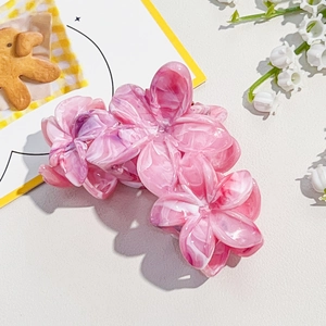 Close-up of resin plumeria hair claw clip with pink and white marble texture