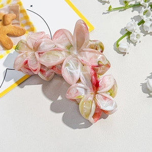Detailed macro view of plumeria hair claw clip with pink and white marble pattern texture