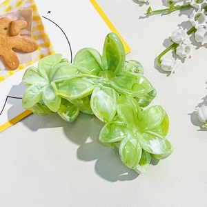Macro detail of marble green flower hair claw clip with glossy acrylic finish
