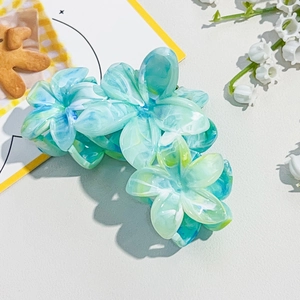 Detailed macro view of three plumeria flower hair claws with blue-green marble texture