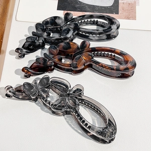Macro shot of three glossy butterfly banana hair clips with tortoiseshell and ink patterns